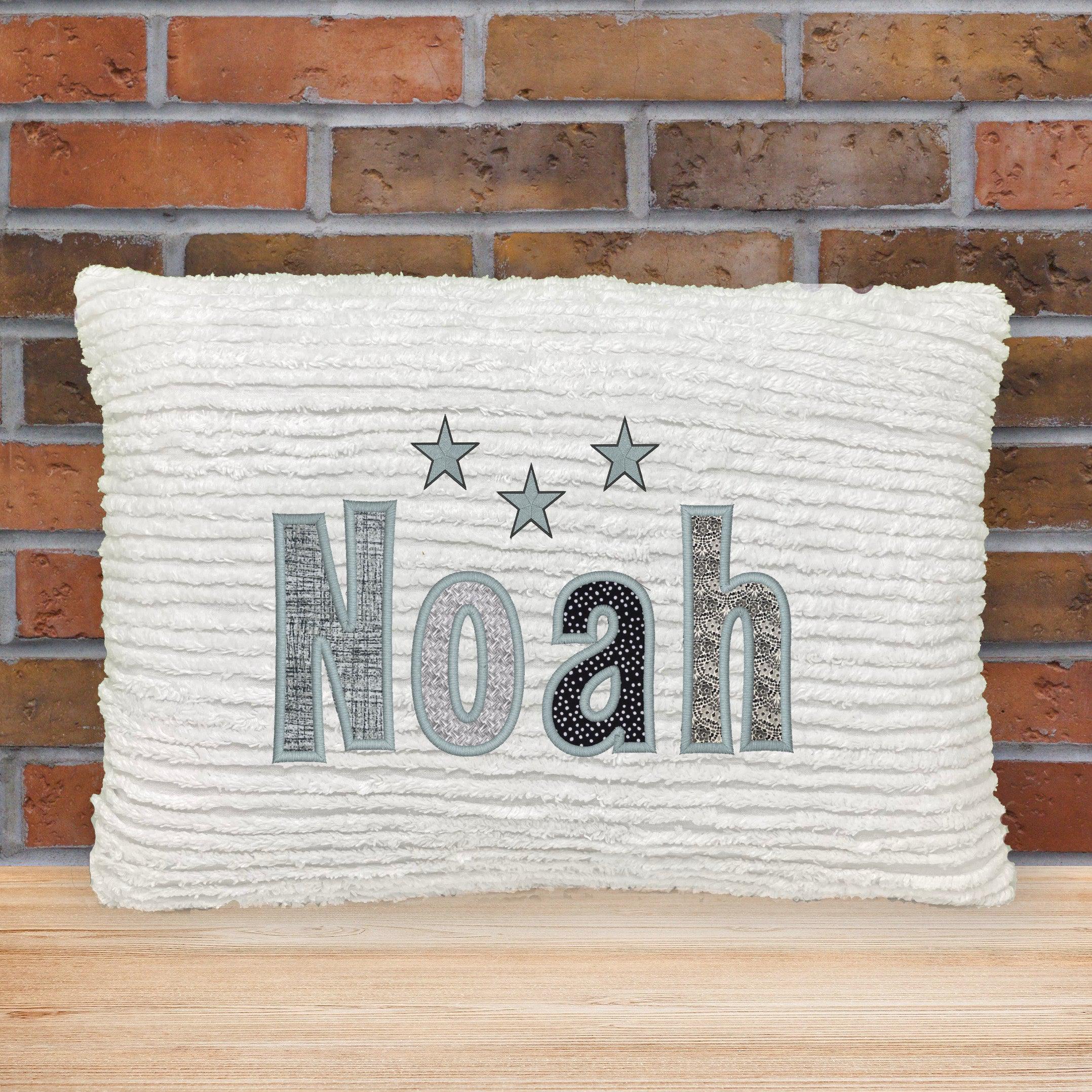 White chenille name pillow with gray and black appliqued letters and stars.