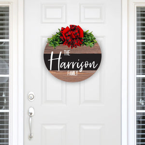 personalized stained wood wreath with family name. red and black plaid with red bow and greenery. 18 inches round solid wood