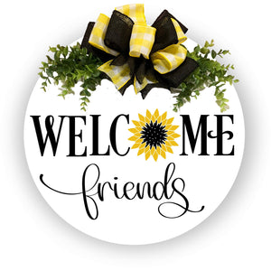 White painted 18 inch wood round door hanger.  welcome friends text with yellow and black sunflower. yellow and white plaid and black bow with greenery